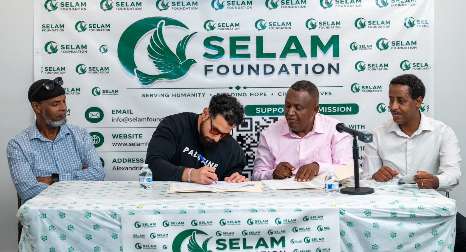 Selam Foundation representatives seated at a branded table during an official signing ceremony