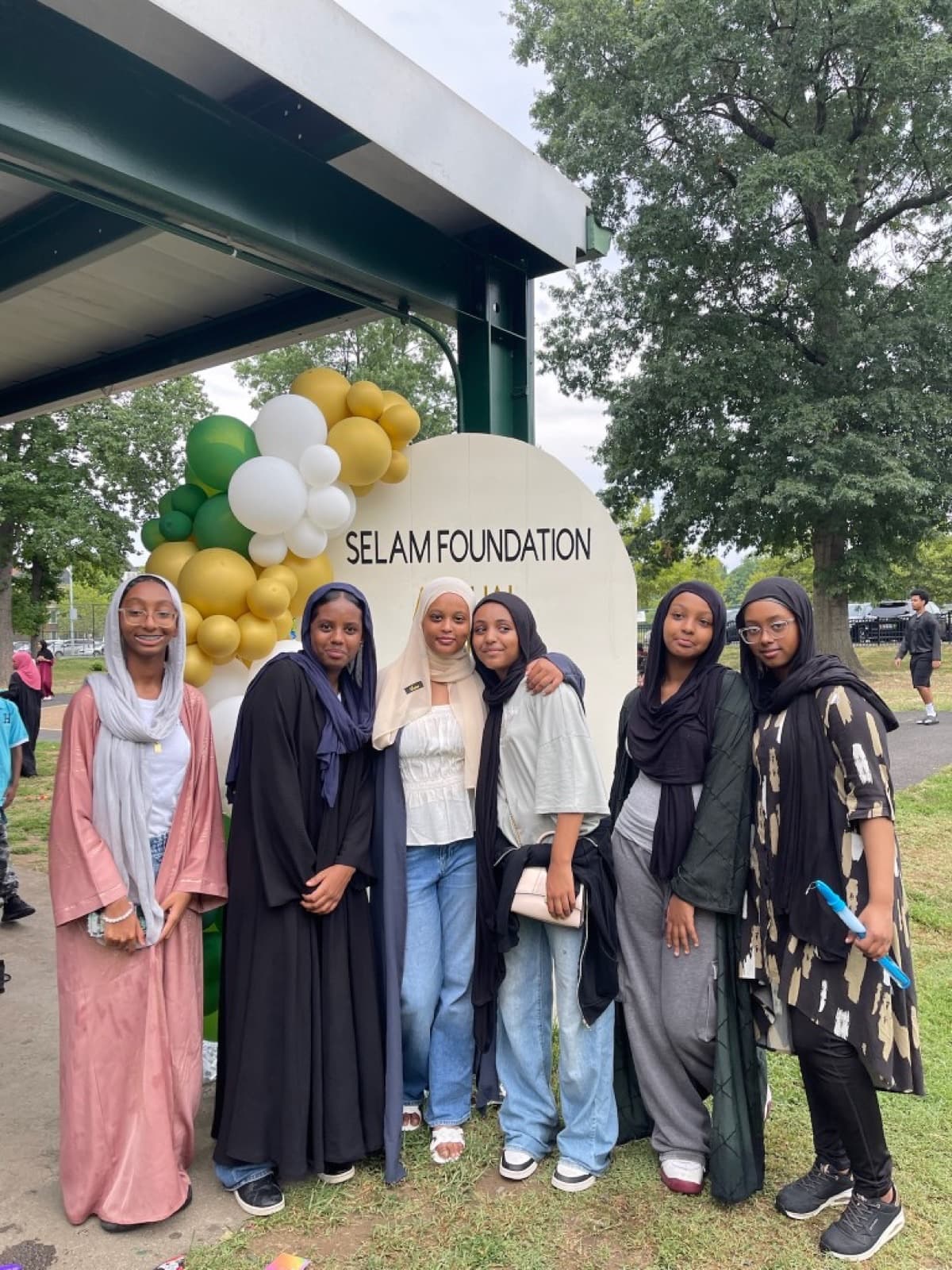 Young women pose together in front of a Selam Foundation Annual event sign
